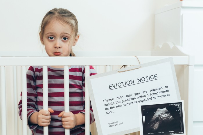 older child in cot with funny eviction notice pinned on it
