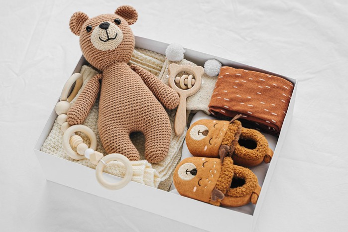 box with teddy bear and baby shoes and other baby stuff in it