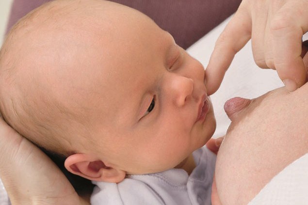 stroking newborn's cheek to encourage rooting reflex