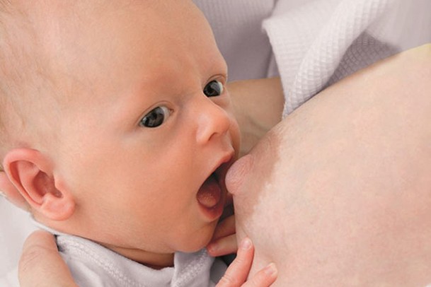 newborn opening mouth wide to latch onto nipple