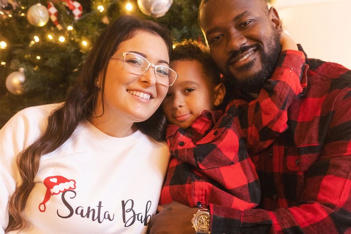 family Christmas picture with Santa baby on jumper revealing pregnancy