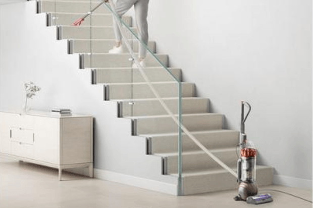 man vacuuming the stairs with a Dyson vacuum